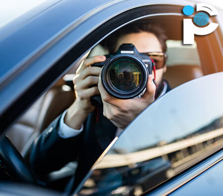 An investigator taking a photo from inside a car using a DSLR camera