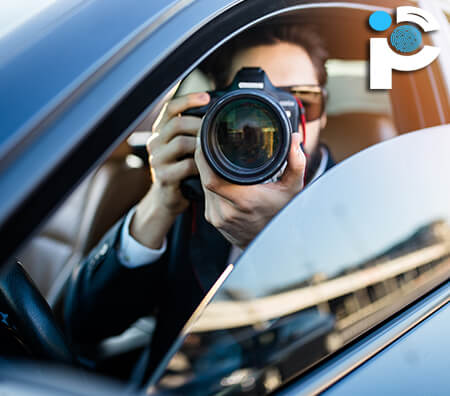 Private investigator taking photos from inside a car with a DSLR camera