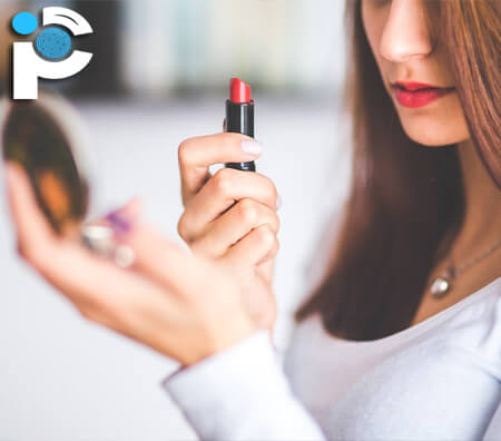 A woman applying lipstick and looking in a mirror