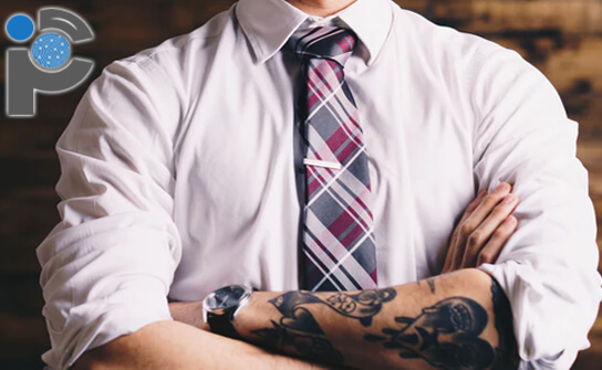 A suited man with tattoos on his arms