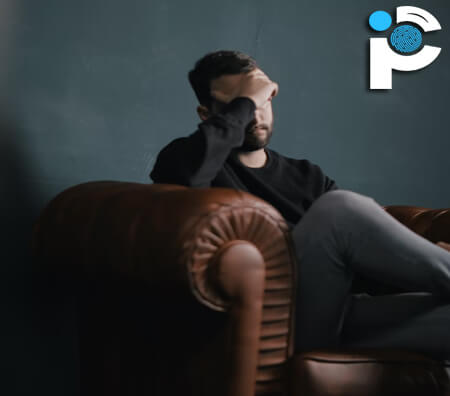 Sad man sitting on a sofa with a hand on his face