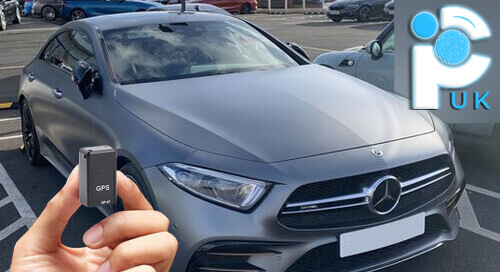 Holding a GPS tracker in front of a Mercedes car