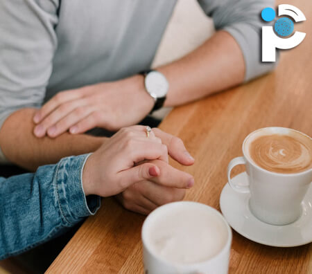 Couple holding hands while drinking coffee
