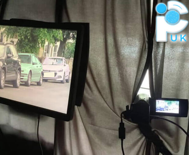 Curtains surrounding a video camera mounted inside a vehicle, pointing outwards, with a monitor inside displaying the camera's live feed