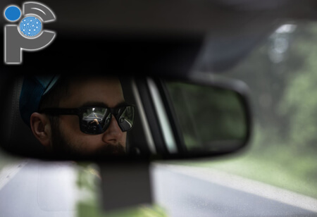 Man wearing sunglasses in a rear view mirror